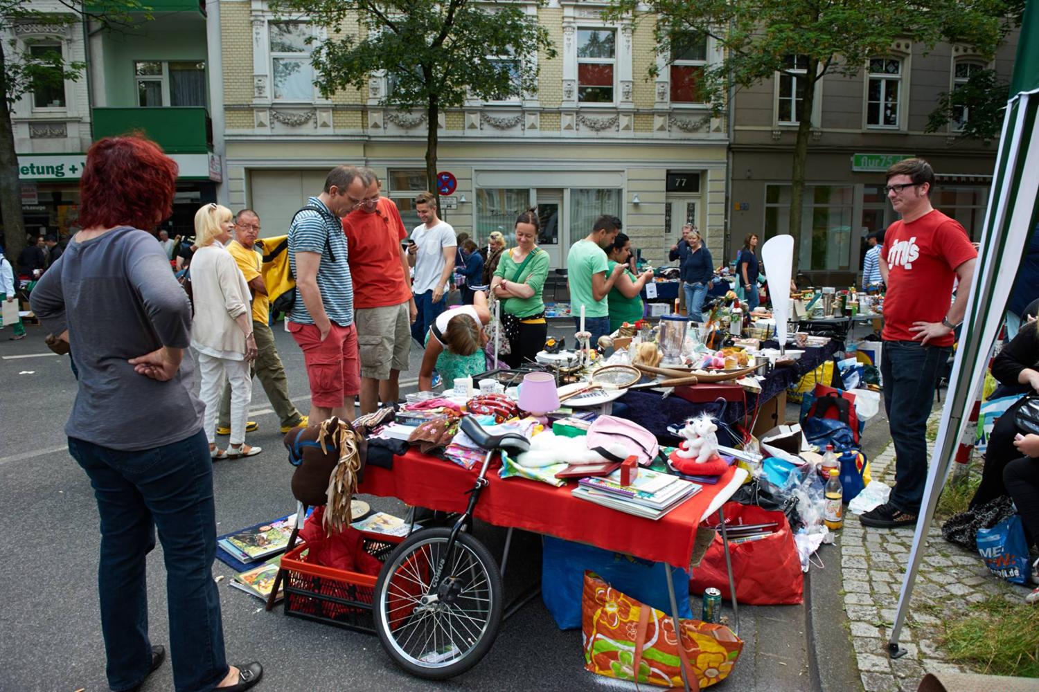 Besucherinnen und Besucher stöbern an einem Trödelstand mit Büchern, Spielzeug und Geschirr.